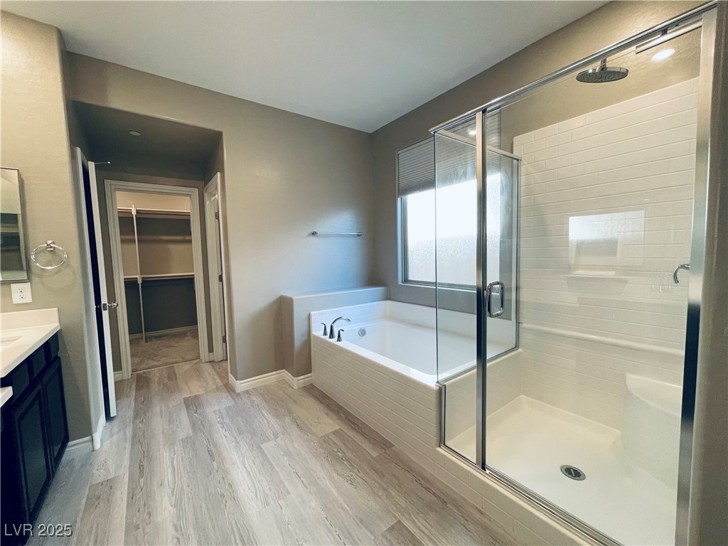 930 Bayberry Ridge Street Henderson, NV 89052 - Photo 27 of 40 Full bathroom with vanity, a shower stall, a walk in closet, a bath, and light wood-style floors