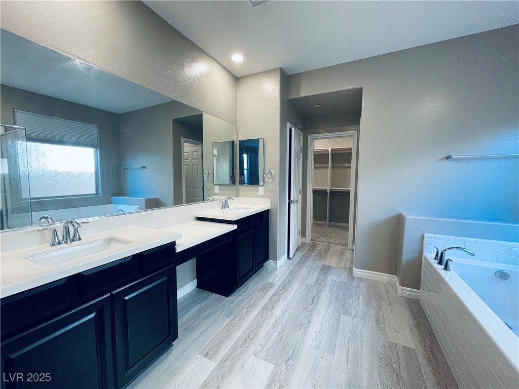 930 Bayberry Ridge Street Henderson, NV 89052 - Photo 31 of 40 Bathroom featuring a garden tub, double vanity, a spacious closet, light wood-style floors, and recessed lighting