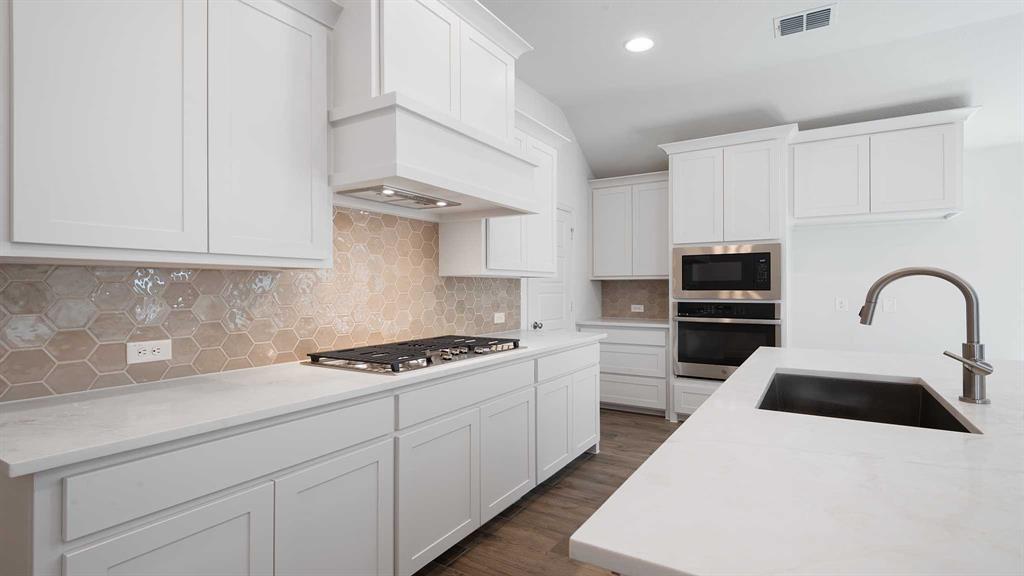 6108 Vester Trail Fate, TX 75087 - Photo 11 of 21 a kitchen with kitchen island a sink stainless steel appliances and cabinets
