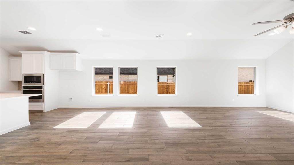 6108 Vester Trail Fate, TX 75087 - Photo 9 of 21 a view of an empty room with window and wooden floor