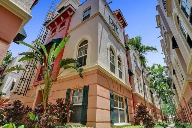 front view of a building with a yard and palm trees