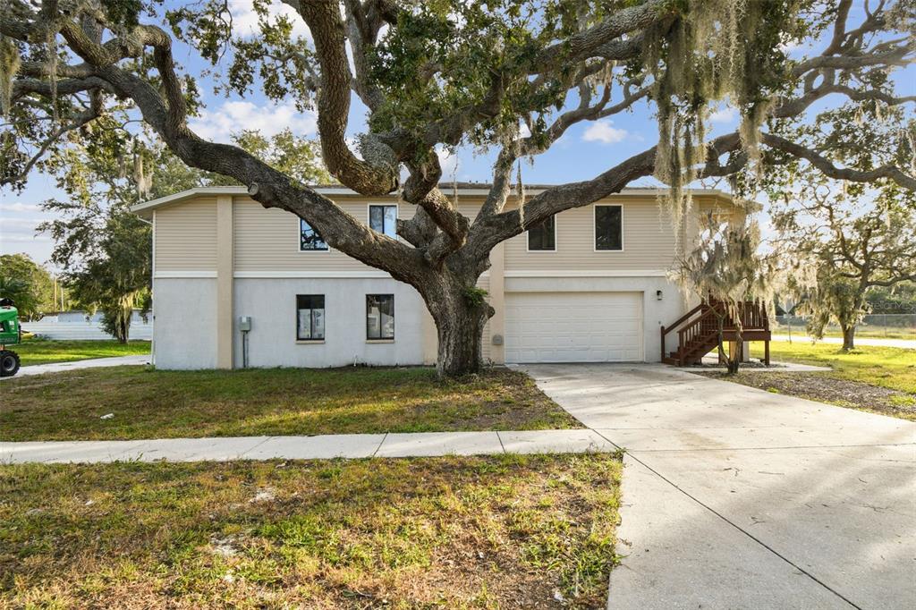 1734 Rumar Lane, Unit A Holiday, FL 34691 - Photo 3 of 100 a view of a white house next to a yard with a large tree