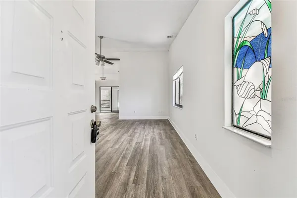 an empty room with wooden floor fan and windows