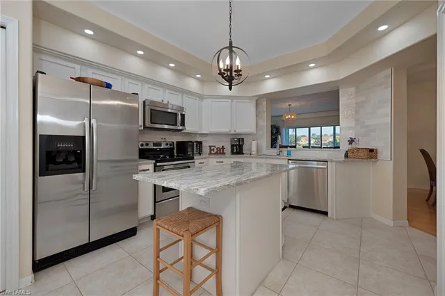 a kitchen with kitchen island granite countertop stainless steel appliances cabinets a sink and a counter top space