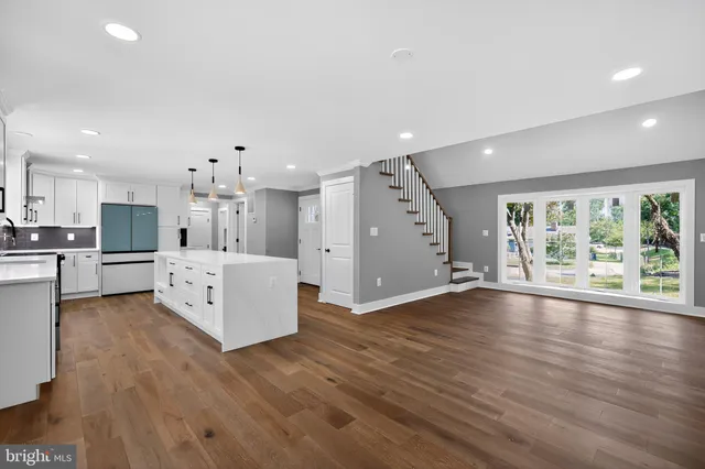 a hall with kitchen island white cabinets and wooden floor