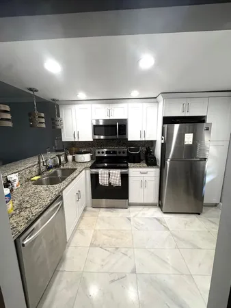 a large kitchen with granite countertop a stove a sink dishwasher and a refrigerator