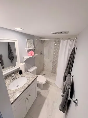 a bathroom with a granite countertop sink toilet and shower