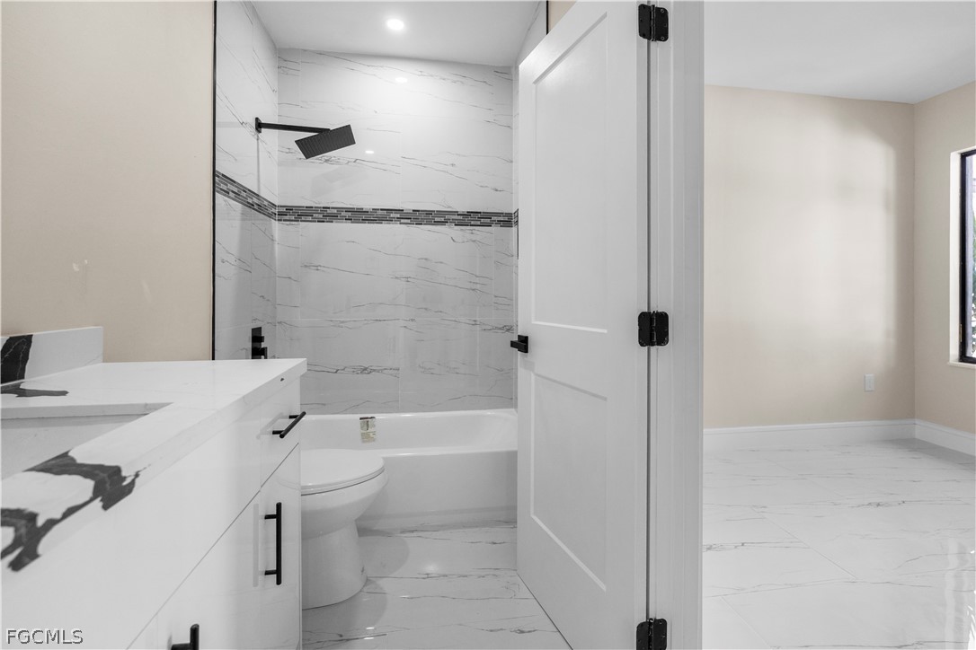 526 Knapp Street Lehigh Acres, FL 33974 - Photo 15 of 37 a bathroom with a bathtub shower sink vanity and toilet