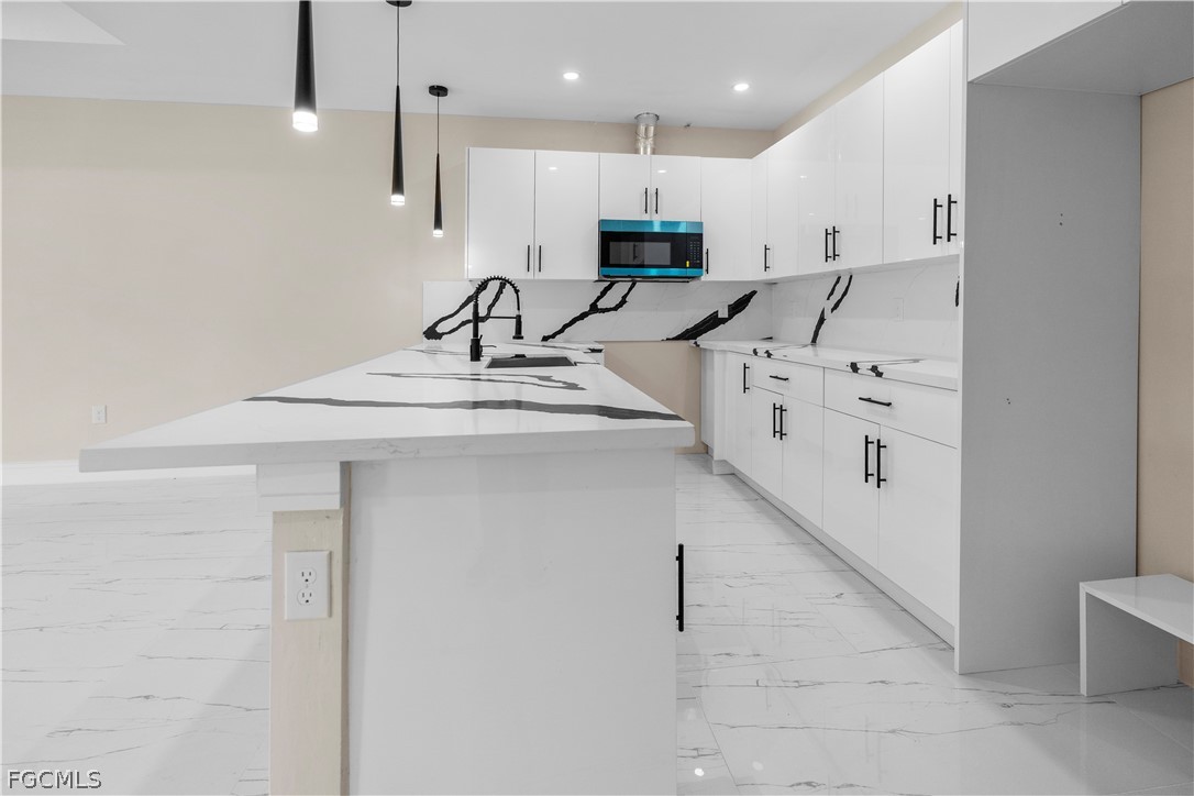 526 Knapp Street Lehigh Acres, FL 33974 - Photo 18 of 37 a kitchen with kitchen island sink stove and white cabinets