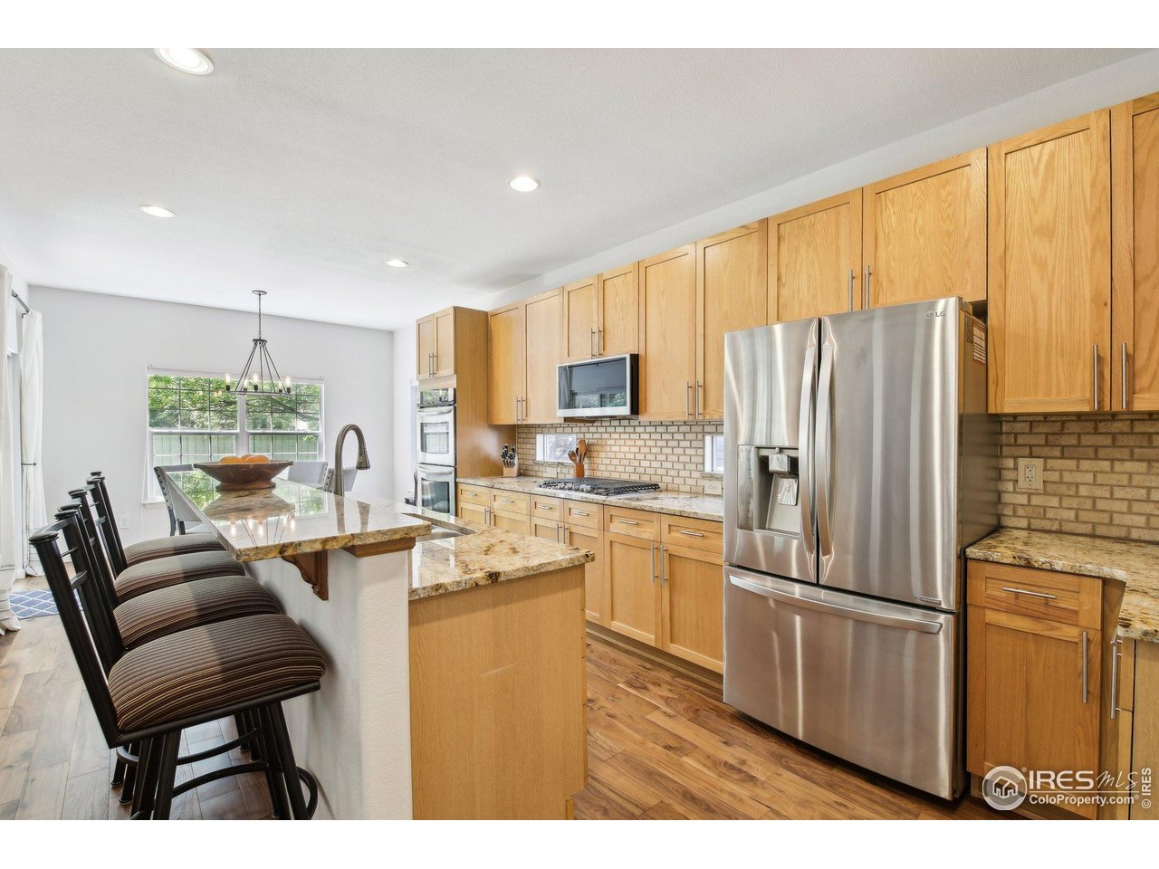 4109 Frederick Circle Longmont, CO 80503 - Photo 7 of 40 a kitchen with stainless steel appliances kitchen island granite countertop a refrigerator a stove and a sink with couches