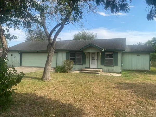 a view of a house with a yard and large tree