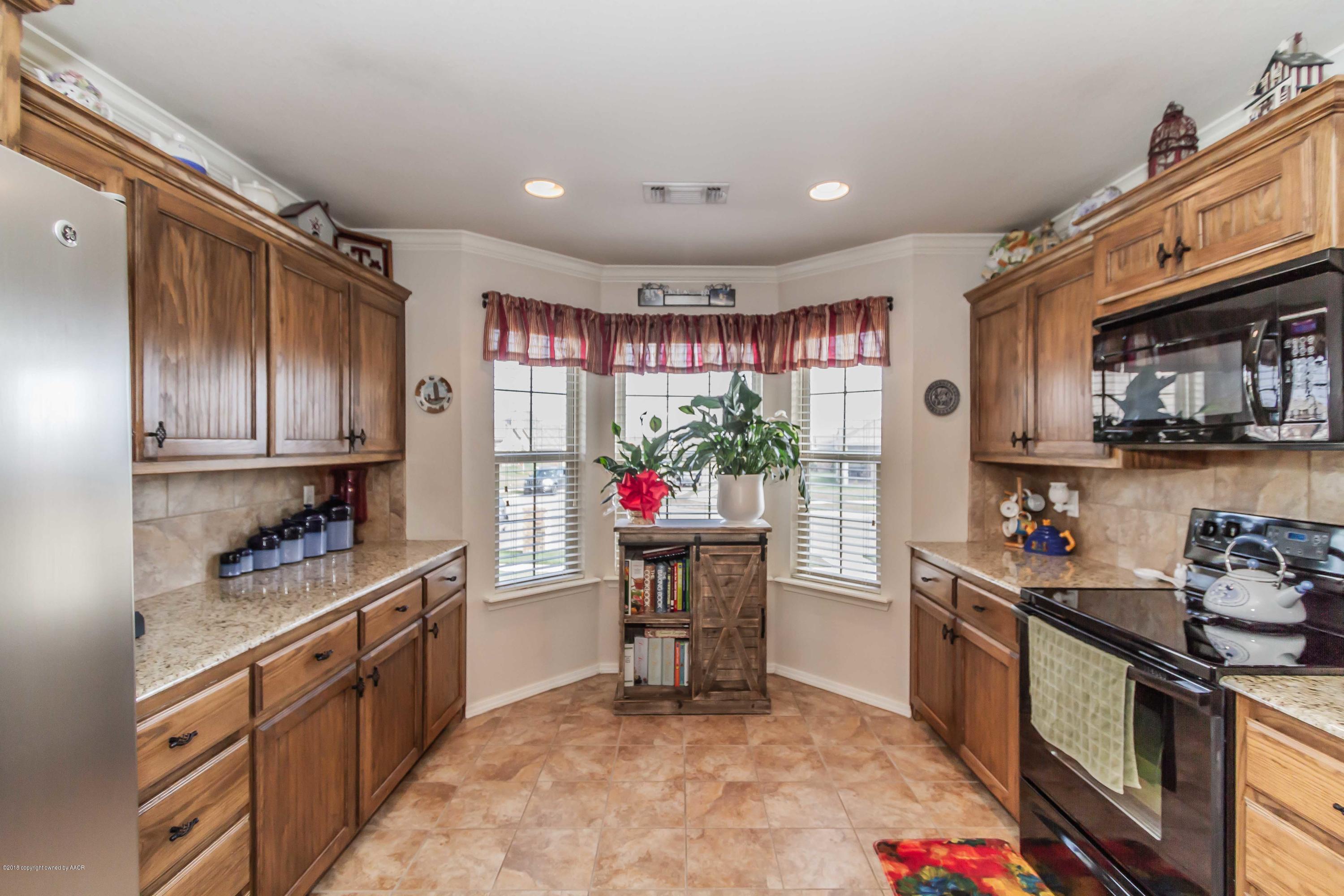 3707 Arden Road Amarillo, TX 79118 - Photo 7 of 32 a kitchen with a refrigerator and wooden cabinets