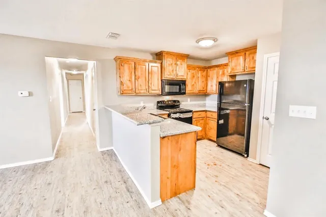 a kitchen that has a lot of cabinets a sink and a wooden floor