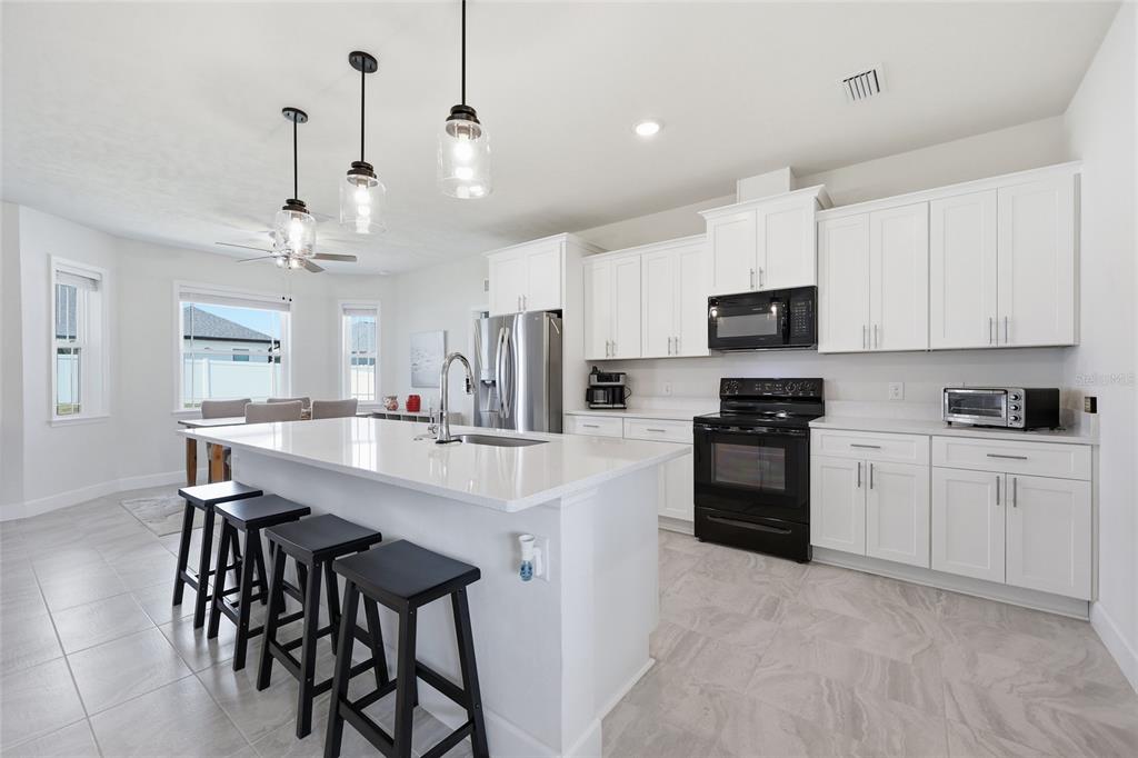 2168 Southwest 245th Terrace Newberry, FL 32669 - Photo 4 of 34 a kitchen with stainless steel appliances kitchen island a table chairs microwave and cabinets