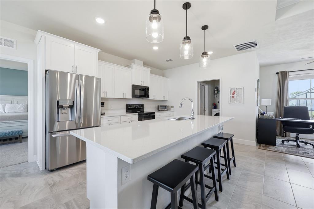 2168 Southwest 245th Terrace Newberry, FL 32669 - Photo 6 of 34 a large kitchen with kitchen island a refrigerator a stove a sink a dining table and chairs