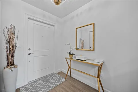 a view of a hallway with wooden floor and a bathroom