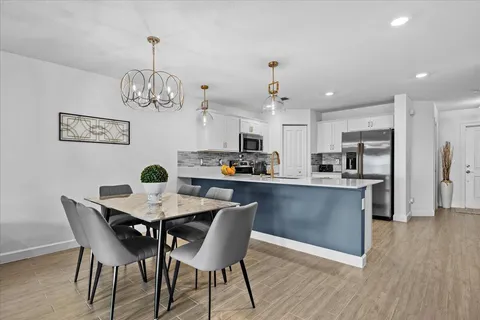 a view of a dining room and livingroom with furniture wooden floor a chandelier