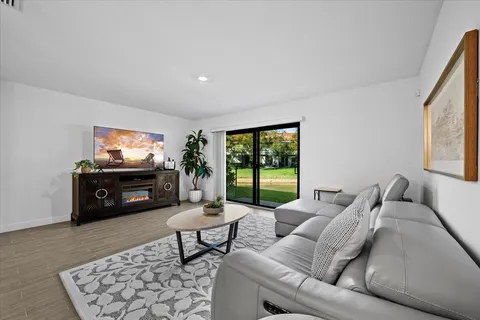 a living room with furniture a flat screen tv and a floor to ceiling window