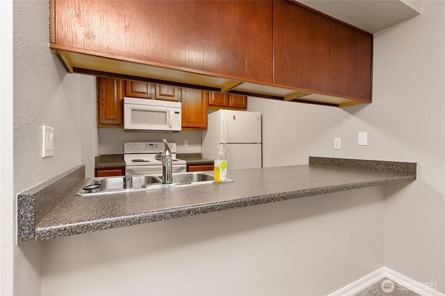 a kitchen with stainless steel appliances granite countertop a sink a stove and a microwave with granite countertops