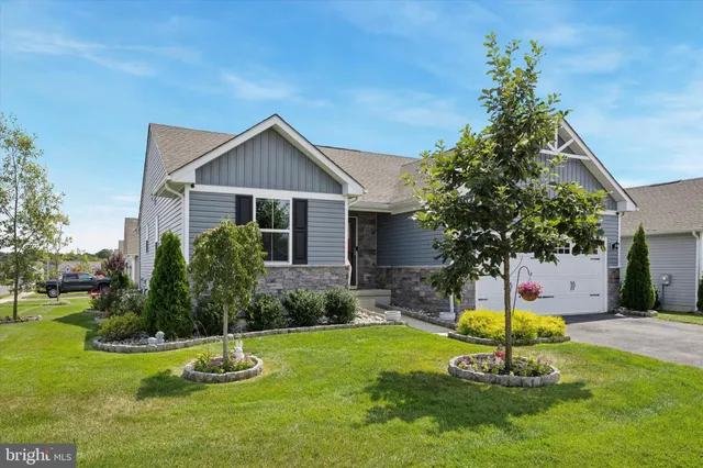 a front view of yellow house with a yard and palm trees