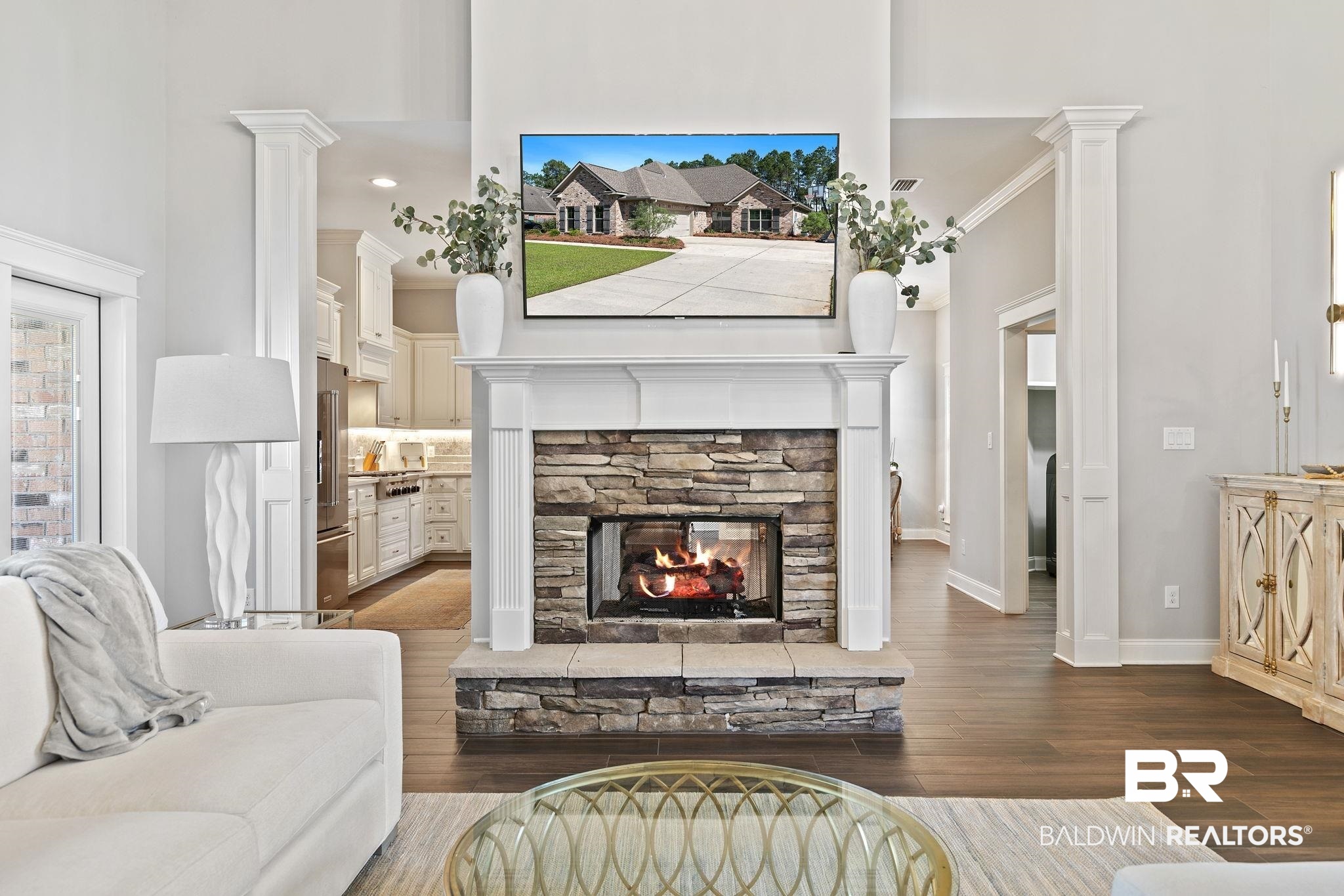 31911 Bobwhite Road Daphne, AL 36527 - Photo 10 of 85 Living room featuring decorative columns, dark wood finished floors, a stone fireplace, a high ceiling, and ornamental molding