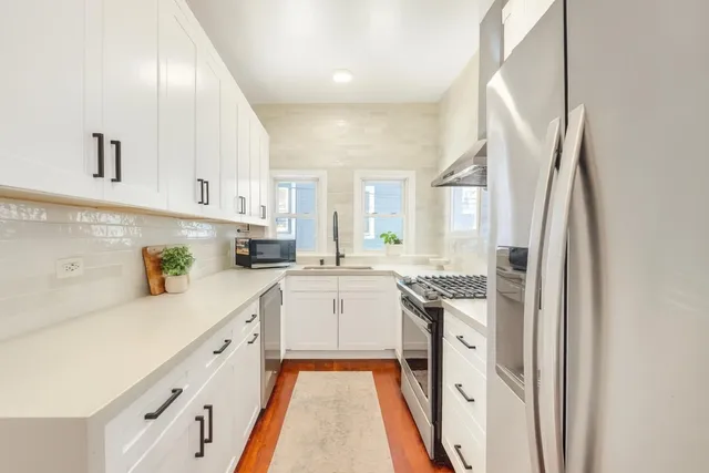 a kitchen with stainless steel appliances granite countertop a refrigerator a stove and white cabinets