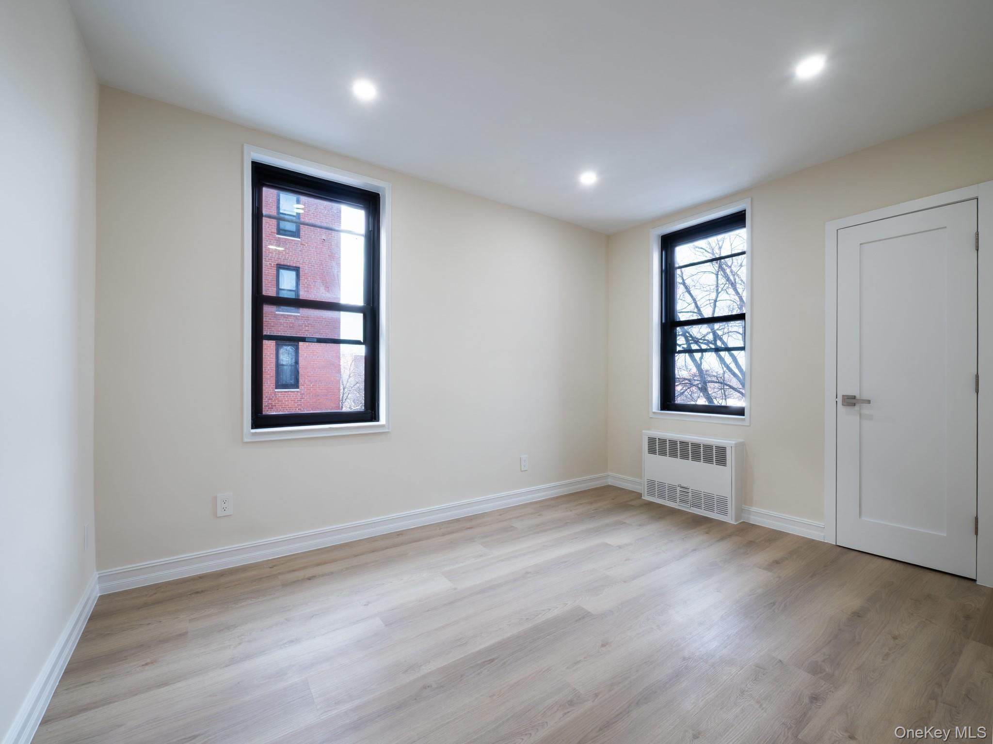 139-15 83rd Avenue, Unit 423 Queens, NY 11435 - Photo 11 of 24 Unfurnished room with light wood finished floors, radiator heating unit, healthy amount of natural light, and recessed lighting