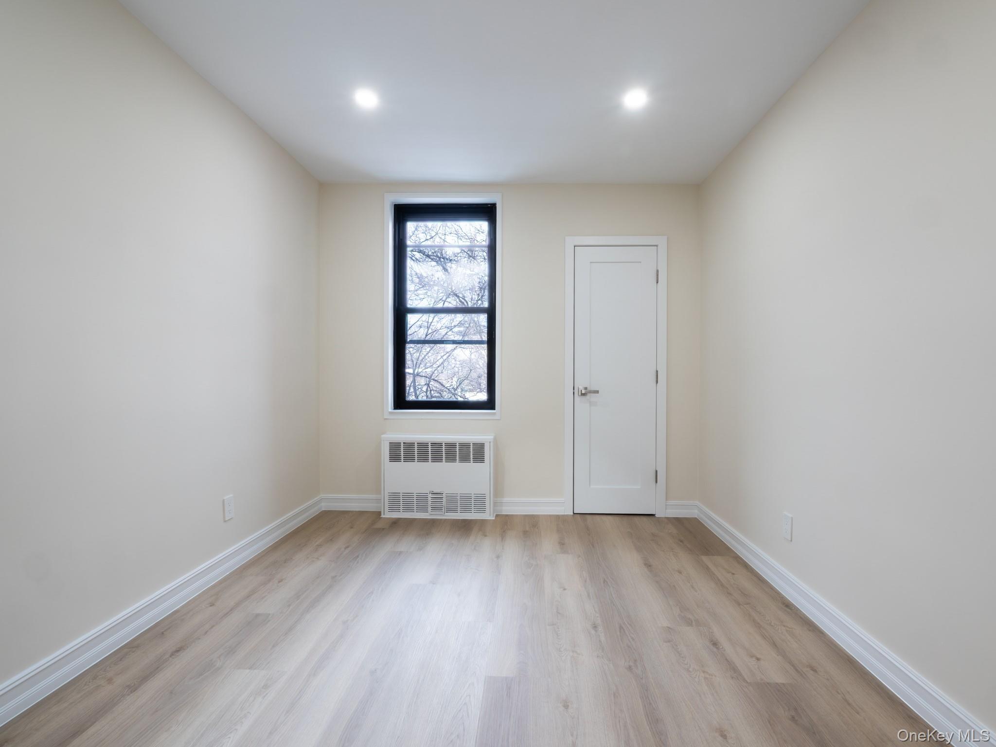 139-15 83rd Avenue, Unit 423 Queens, NY 11435 - Photo 12 of 24 Unfurnished room with radiator heating unit and light wood-type flooring
