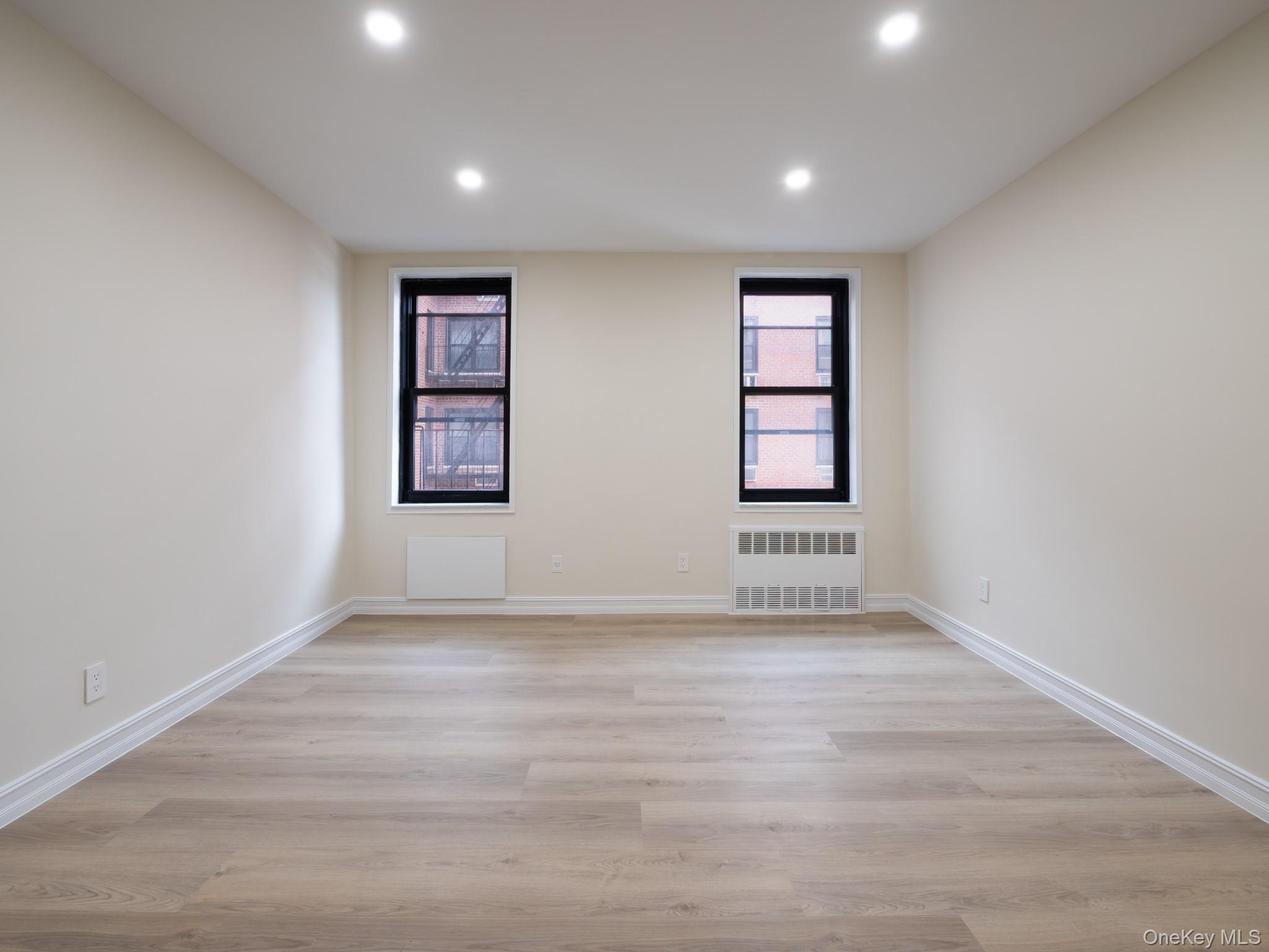 139-15 83rd Avenue, Unit 423 Queens, NY 11435 - Photo 16 of 24 Spare room featuring light wood-style flooring, recessed lighting, and radiator heating unit