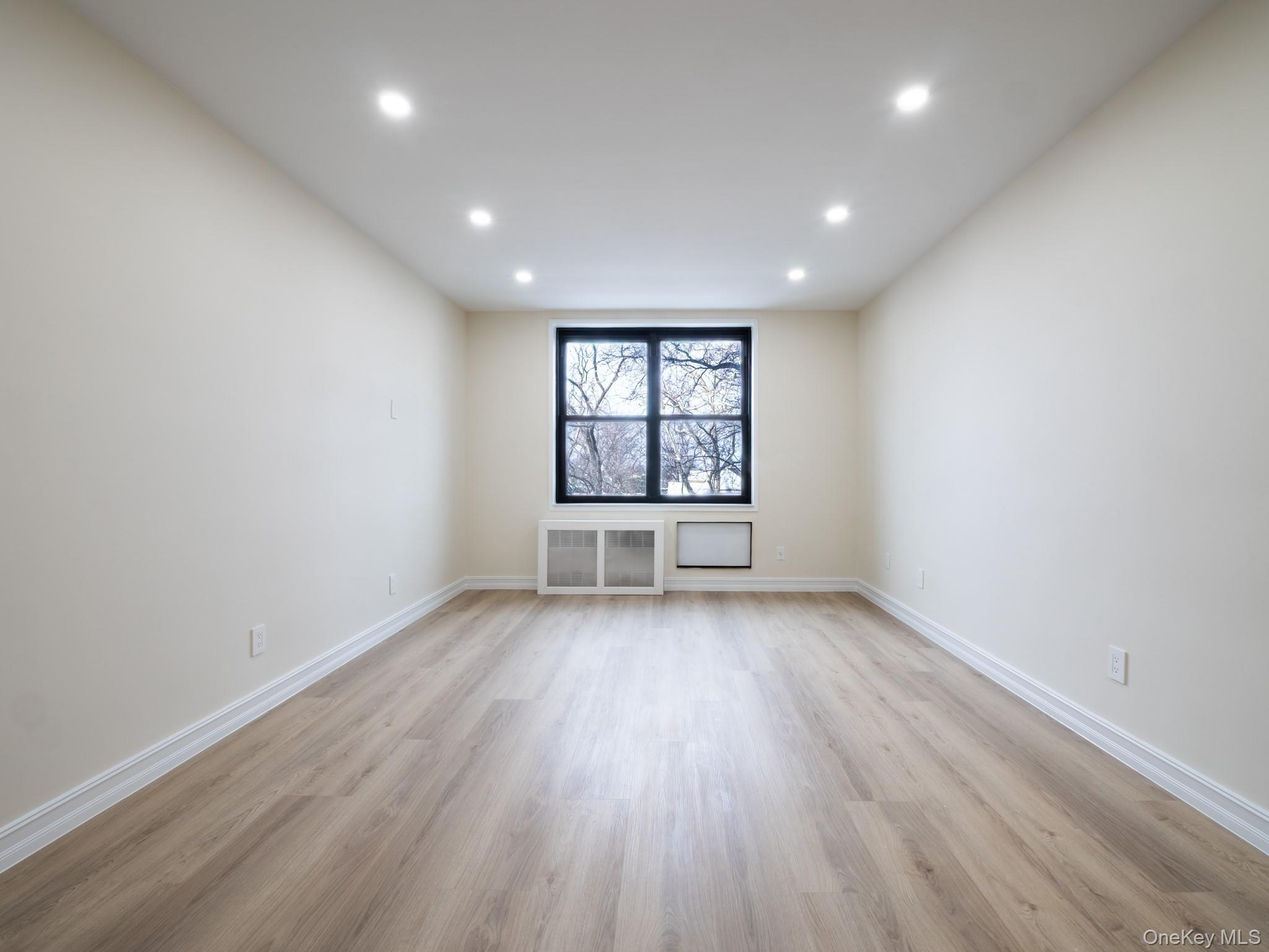 139-15 83rd Avenue, Unit 423 Queens, NY 11435 - Photo 4 of 24 Unfurnished room with light wood-type flooring, radiator, and recessed lighting