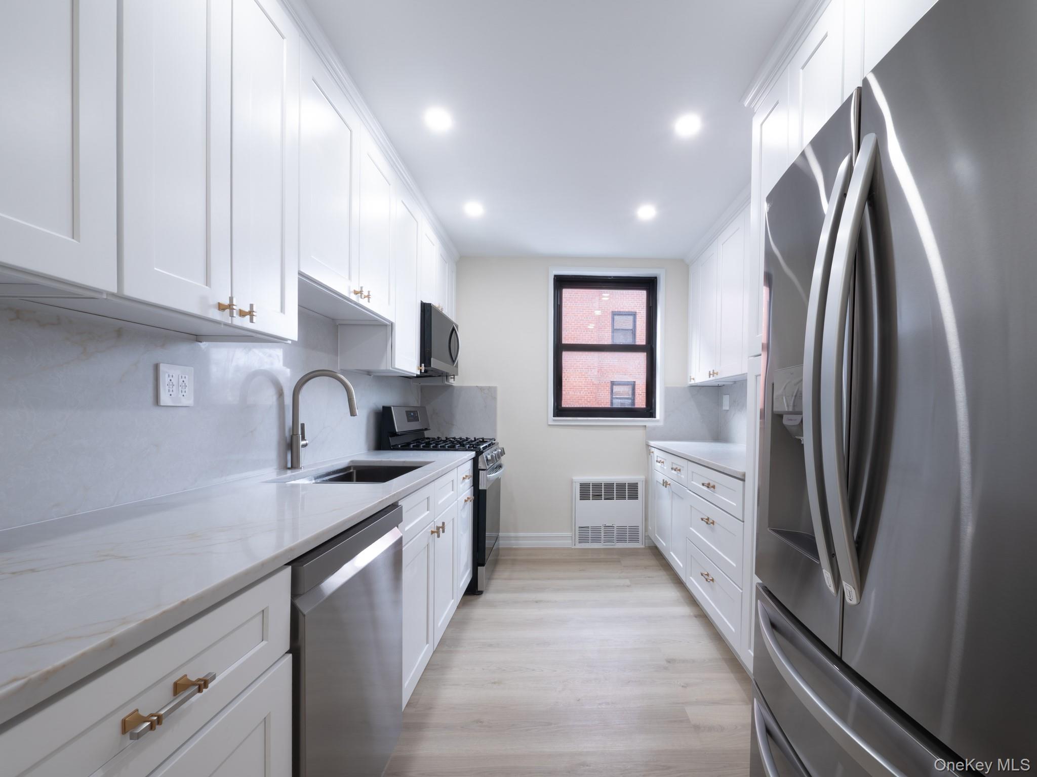 139-15 83rd Avenue, Unit 423 Queens, NY 11435 - Photo 8 of 24 Kitchen featuring stainless steel appliances, white cabinetry, decorative backsplash, light stone counters, and recessed lighting
