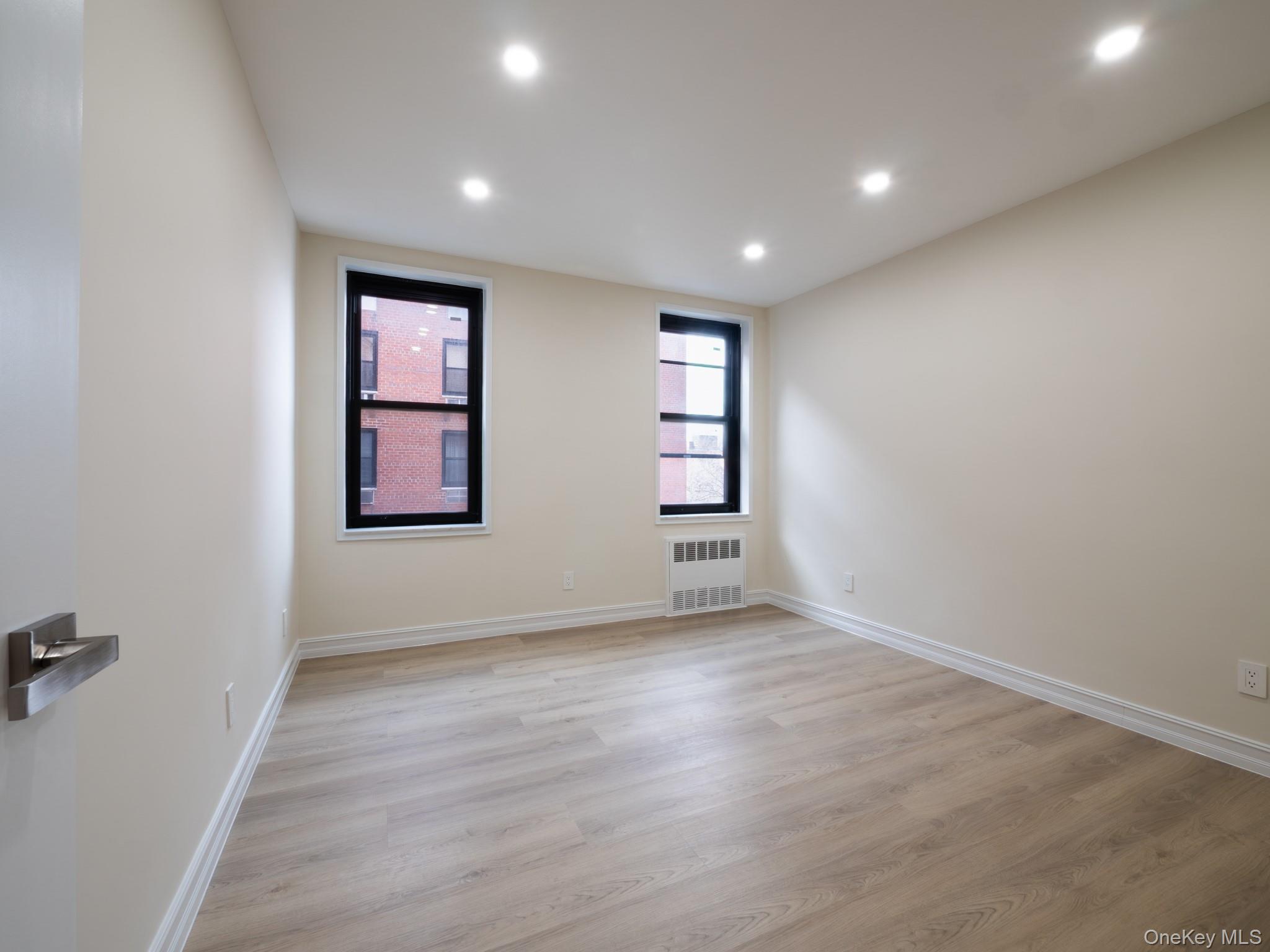 139-15 83rd Avenue, Unit 423 Queens, NY 11435 - Photo 10 of 24 Empty room featuring light wood-type flooring, recessed lighting, and radiator