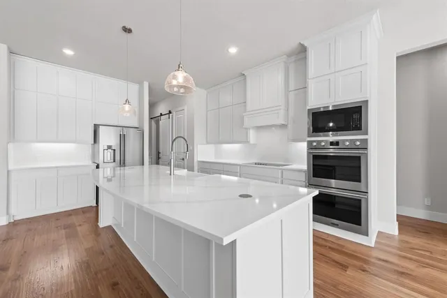a kitchen with kitchen island granite countertop a refrigerator a sink and white cabinets