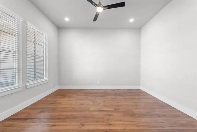 an empty room with wooden floor and a ceiling fan