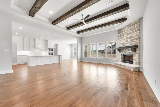 a view of an empty room with wooden floor fireplace and a window