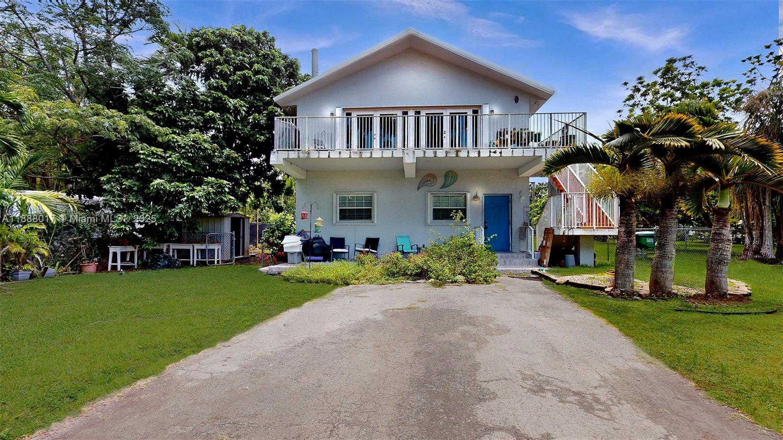 18475 Southwest 204th Street Miami, FL 33187 - Photo 5 of 41 a front view of a house with a garden and trees