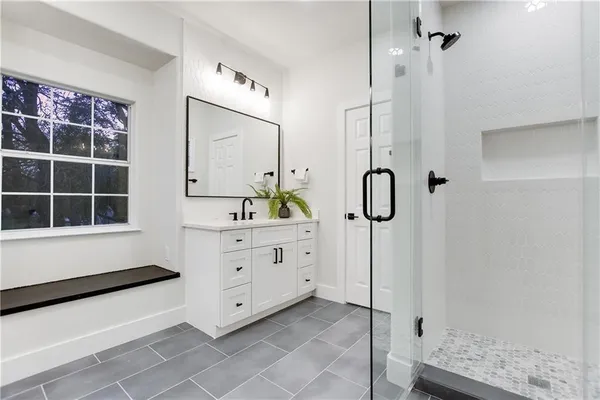 a spacious en suite bathroom with a double vanity sink a mirror and a