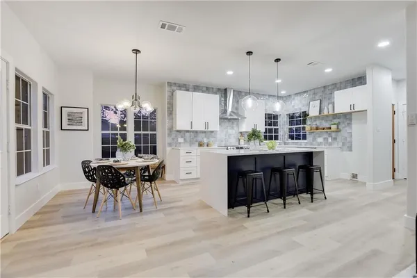 a kitchen with stainless steel appliances granite countertop a stove a sink a oven a dining table and chairs with wooden floor