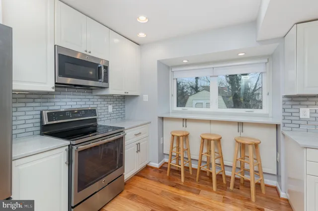 a kitchen with stainless steel appliances granite countertop a refrigerator a stove top oven a sink and dishwasher with wooden floor