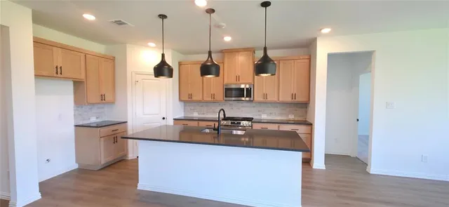 a kitchen with stainless steel appliances granite countertop a sink a stove and a refrigerator