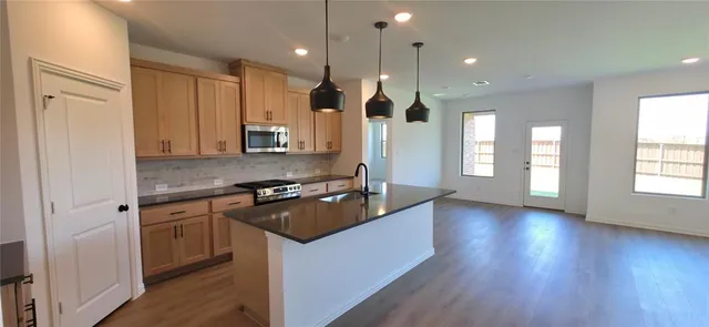 a kitchen with stainless steel appliances granite countertop a stove a sink dishwasher and a refrigerator with wooden floor