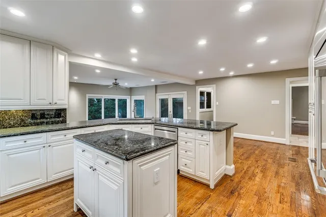 a kitchen with granite countertop a stove and white cabinets
