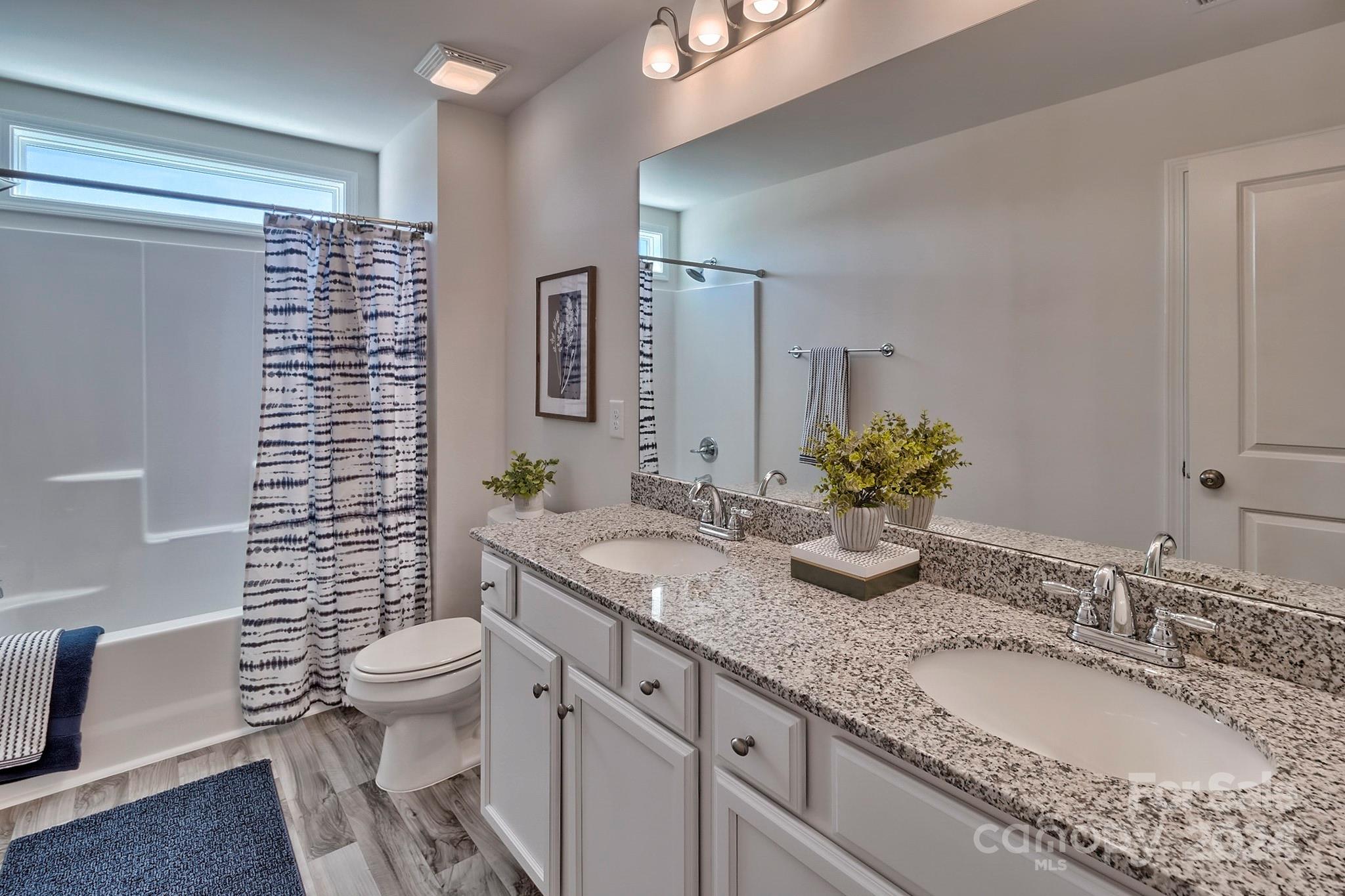 6504 Alanbrook Road, Unit 63 Charlotte, NC 28215 - Photo 16 of 25 a bathroom with a granite countertop sink a toilet a mirror and shower
