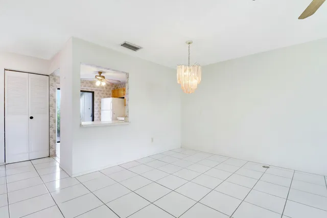 an empty room with windows and chandelier fan