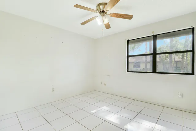 an empty room with windows and fan