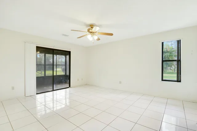 an empty room with windows and ceiling fan