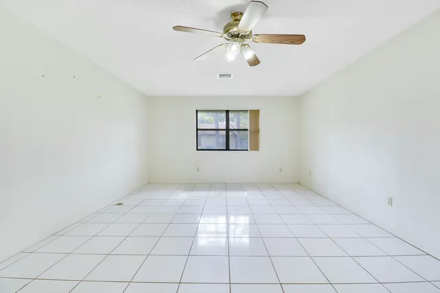 an empty room with windows and ceiling fan