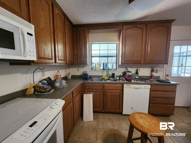 32749 Antietam Road Lillian, AL 36549 - Photo 12 of 47 Kitchen with white appliances, a wealth of natural light, sink, and a textured ceiling