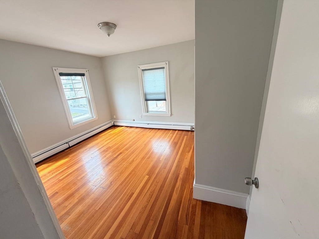 465 High Street, Unit 2 Dedham, MA 02026 - Photo 7 of 12 an empty room with wooden floor and windows
