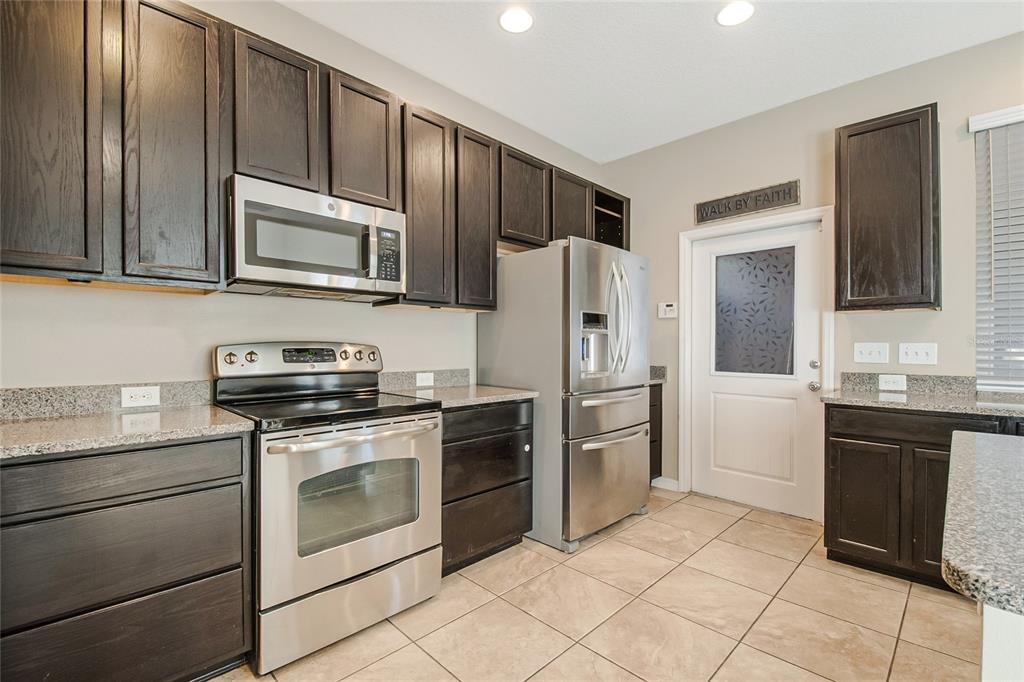 6844 Sundrop Street Harmony, FL 34773 - Photo 20 of 67 a kitchen with stainless steel appliances granite countertop a refrigerator stove and sink